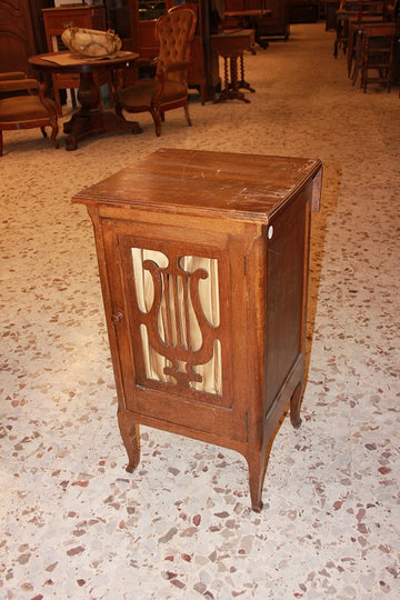 French music cabinet from the 1800s with lyre-shaped carving on the front door