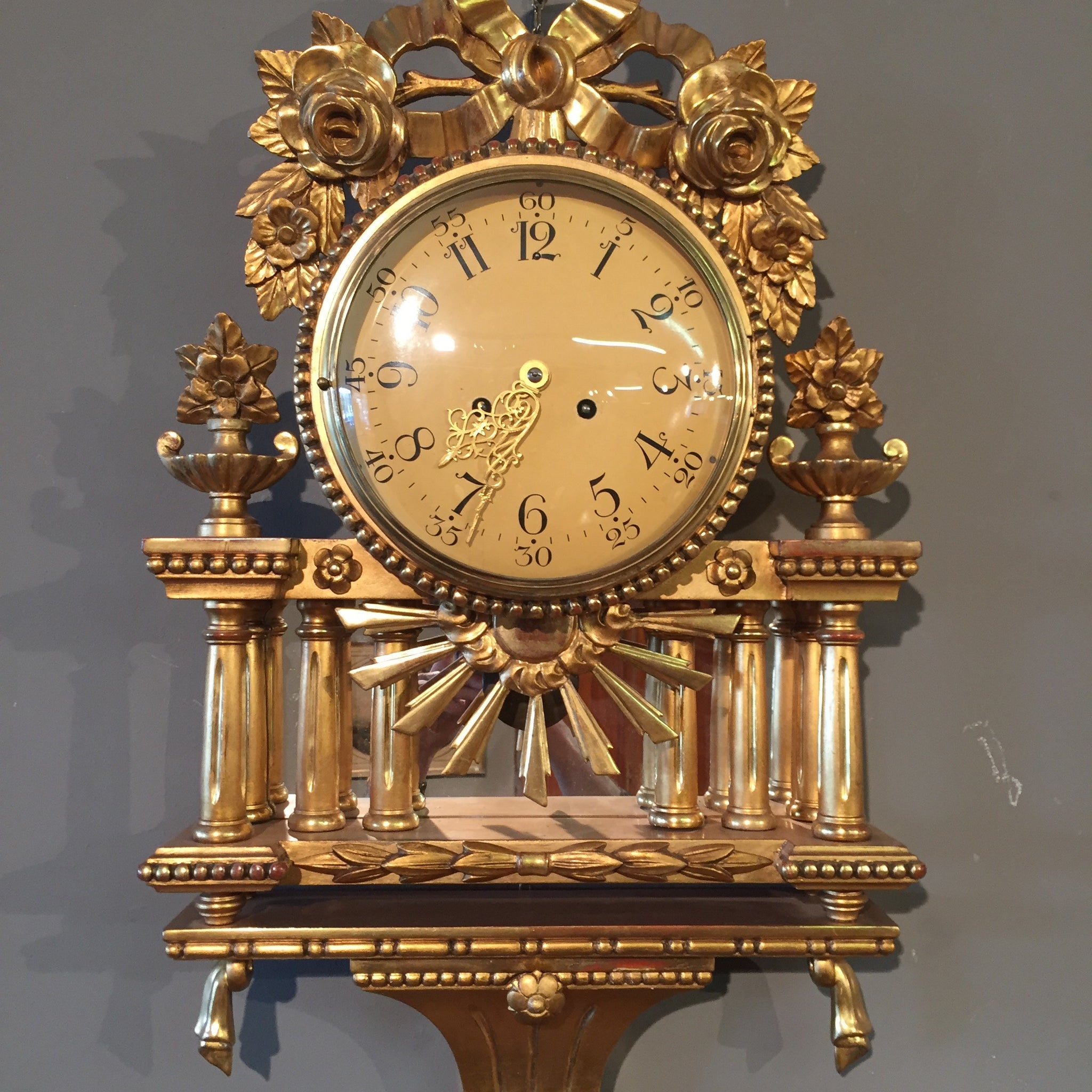 Antique wall clock from the early 1900s in carved gilded wood