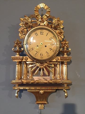 Antique wall clock from the early 1900s in carved gilded wood